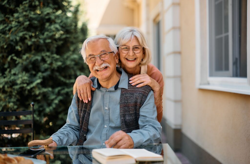 A happy senior couple smiling together outside their independent living community home.