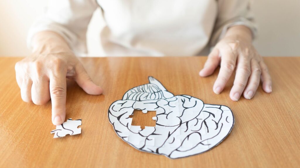 a close-up of a person assembling a brain puzzle with a piece missing to symbolize memory loss.