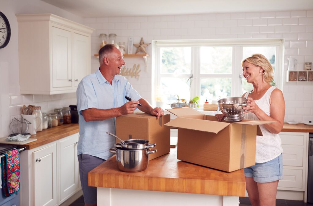A senior couple begin the process of downsizing for retirement by packing up boxes of unneeded kitchen appliances
