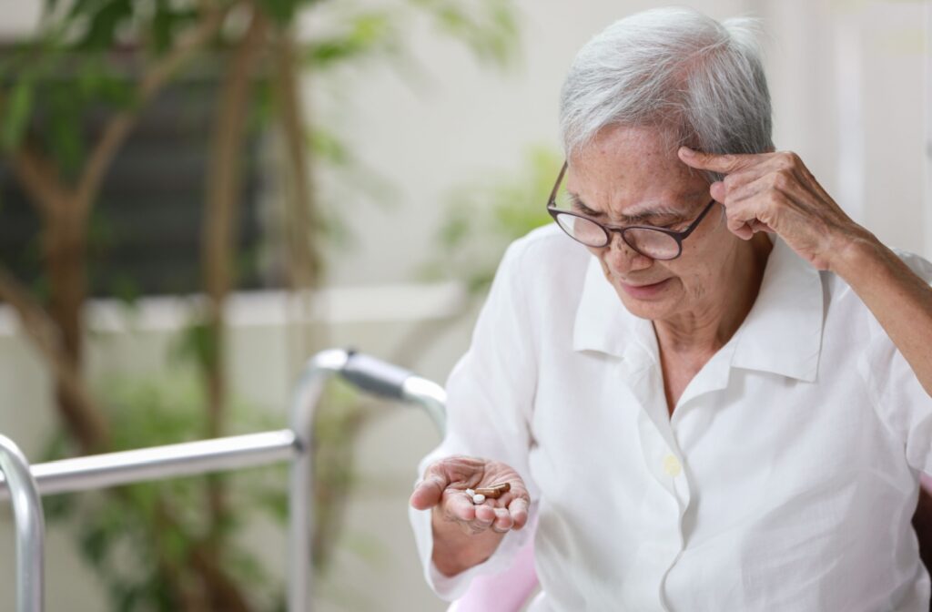 An older adult with memory loss rubbing their forehead and trying to remember if they took their pills.