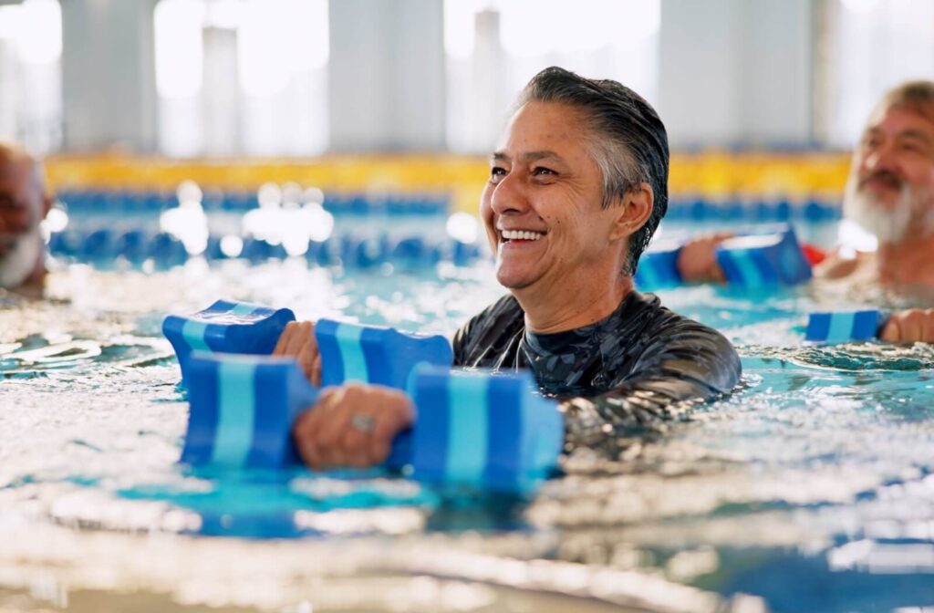 A group of seniors are in a water aerobics class, having fun while exercising.