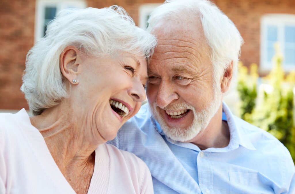 A senior couple laugh together while sitting outside